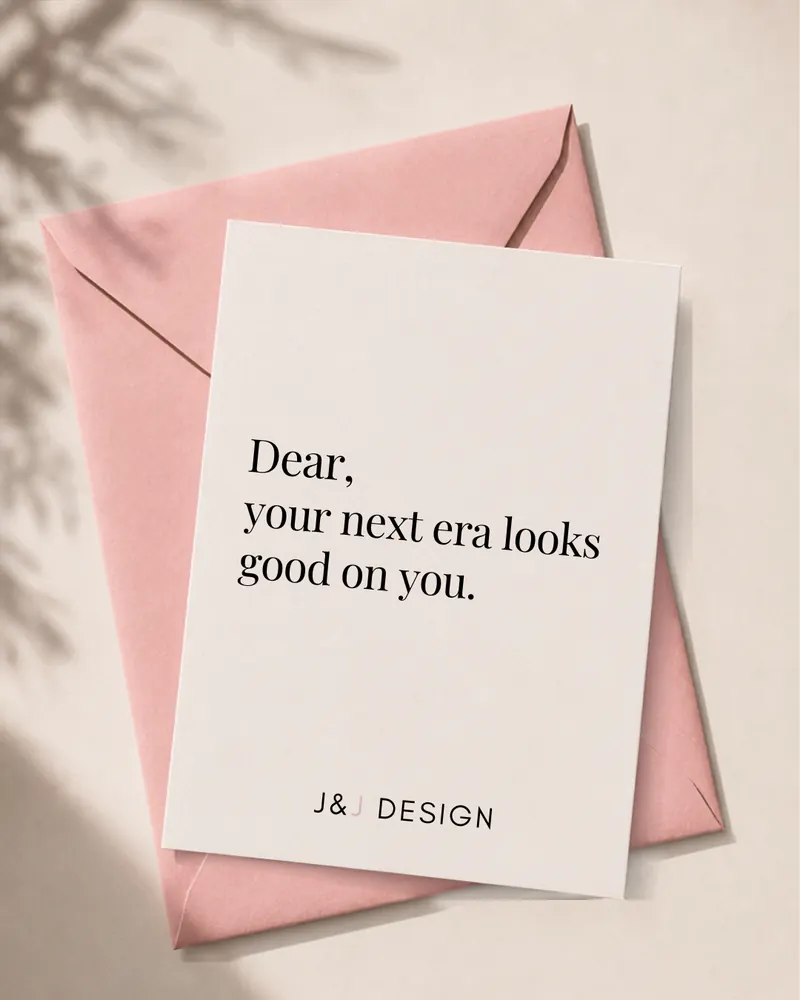 A J&J Design note card on a pink envelope reading: Dear, your next era looks good on you.